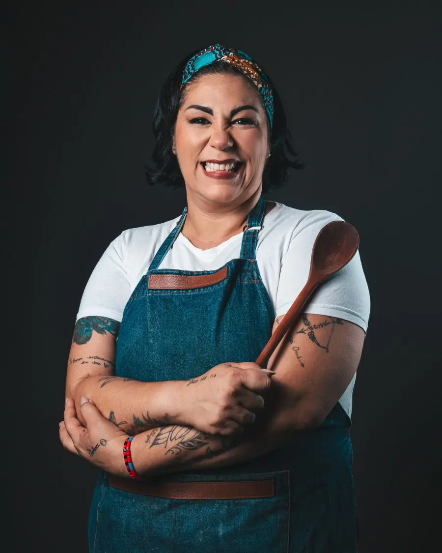 Reena, arms folded, in an apron in the bakery.